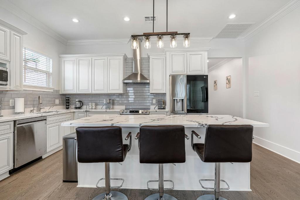 una cocina con armarios blancos y una isla con taburetes. en New 4 Bed luxury house w/Private Heated Pool, en Nueva Orleans