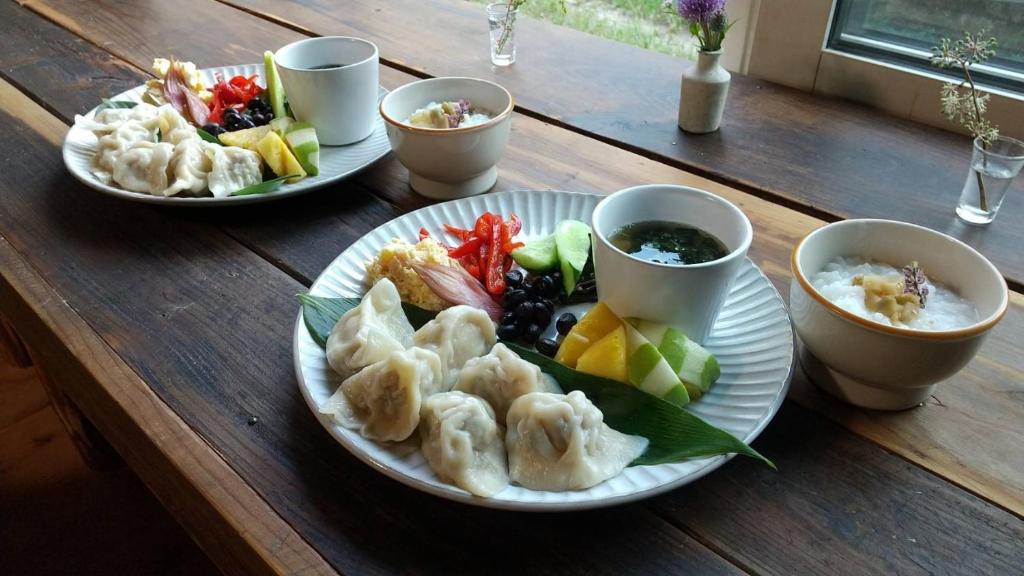 a wooden table with plates of food and bowls of food at Tanehachi Farm Guesthouse - Vacation STAY 29709v in Aomori