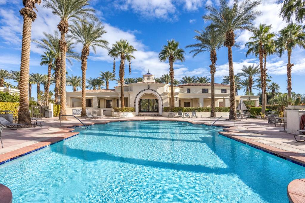 a swimming pool in front of a house with palm trees at Desert Paradise by VARE - Puerta Azul - Pool & Spa in La Quinta