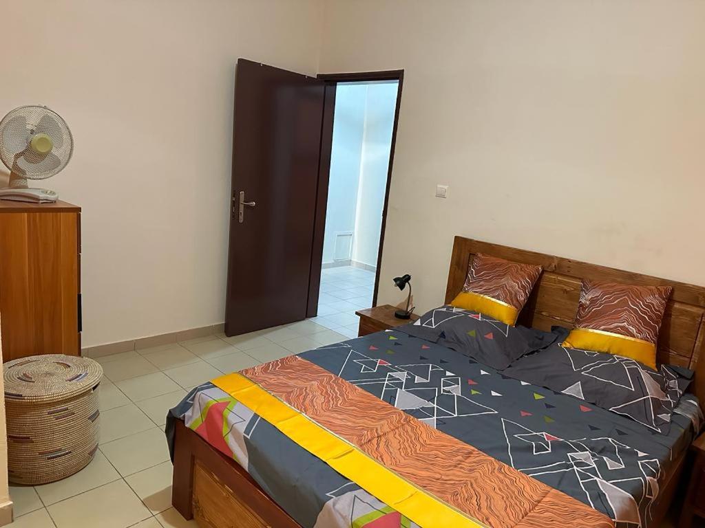 a bedroom with a large bed and a fan at Appartement Spacieux chez Keur Matou - F2 Dakar in Dakar