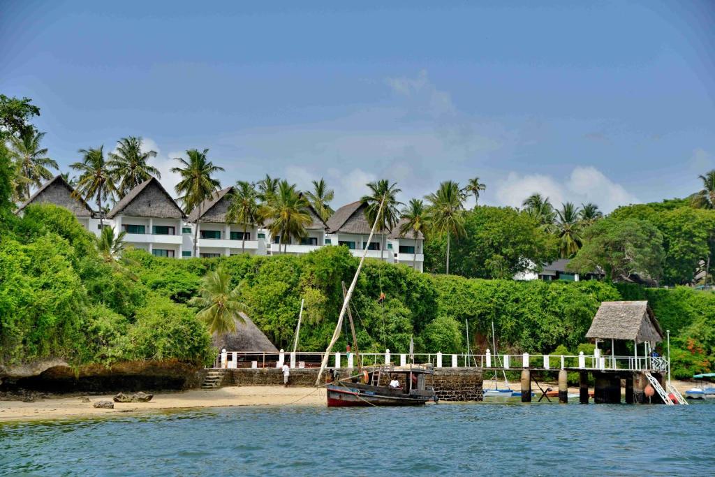 un barco está atracado en una playa con una casa en Mnarani Beach Club en Kilifi