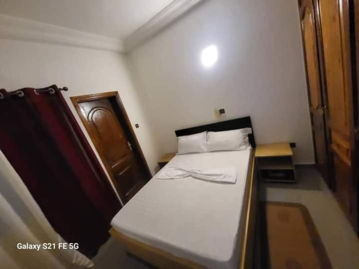 Cette petite chambre comprend un lit avec des draps blancs. dans l'établissement Entrée personnelle fidjrossè, à Cotonou