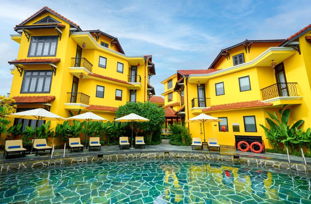 a hotel with a swimming pool in front of a building at Oriental Boutique Hoi An in Hoi An