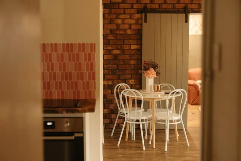 una mesa y sillas en una cocina con una pared de ladrillo en The Karri Hideaway, Pemberton, en Pemberton