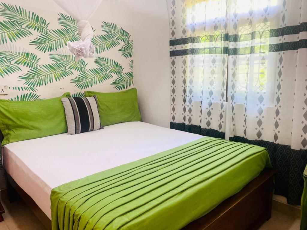 a bed in a room with a green and white wall at Village feel home stay in Sigiriya