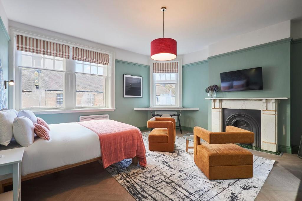 1 dormitorio con paredes verdes, 1 cama y chimenea en Arlington House Hotel - Luxurious Self Check-In Ensuite Rooms in the Centre of Wooler en Wooler