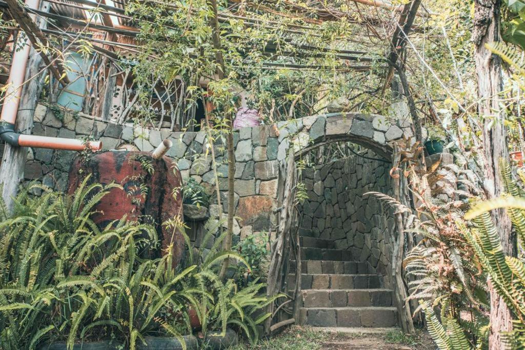 a stone wall with a staircase in a garden at Earthship amazing Cabins with lake view in San Marcos La Laguna