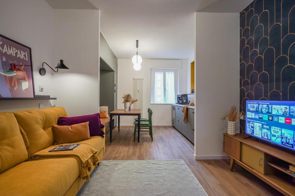 a living room with a yellow couch and a kitchen at Depero di TSS' - Chic, Appena Rinnovato vicino al MART, Supermercato, Ristoranti in Rovereto