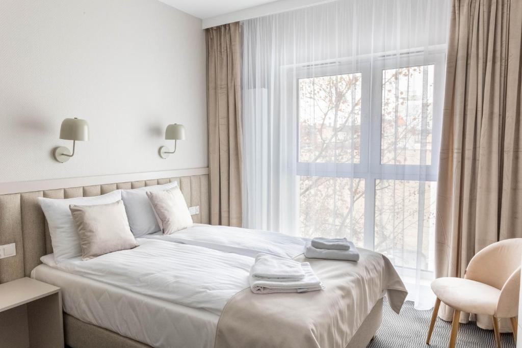 ein weißes Schlafzimmer mit einem Bett und einem Fenster in der Unterkunft Apartamenty Wolności 6 self check-in 24h in Posen