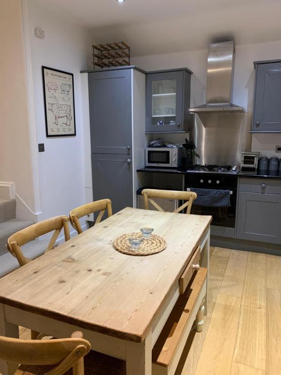 a kitchen with a wooden table with chairs and a kitchen with a stove at The Old Bank House - Ross-on-Wye in Ross on Wye