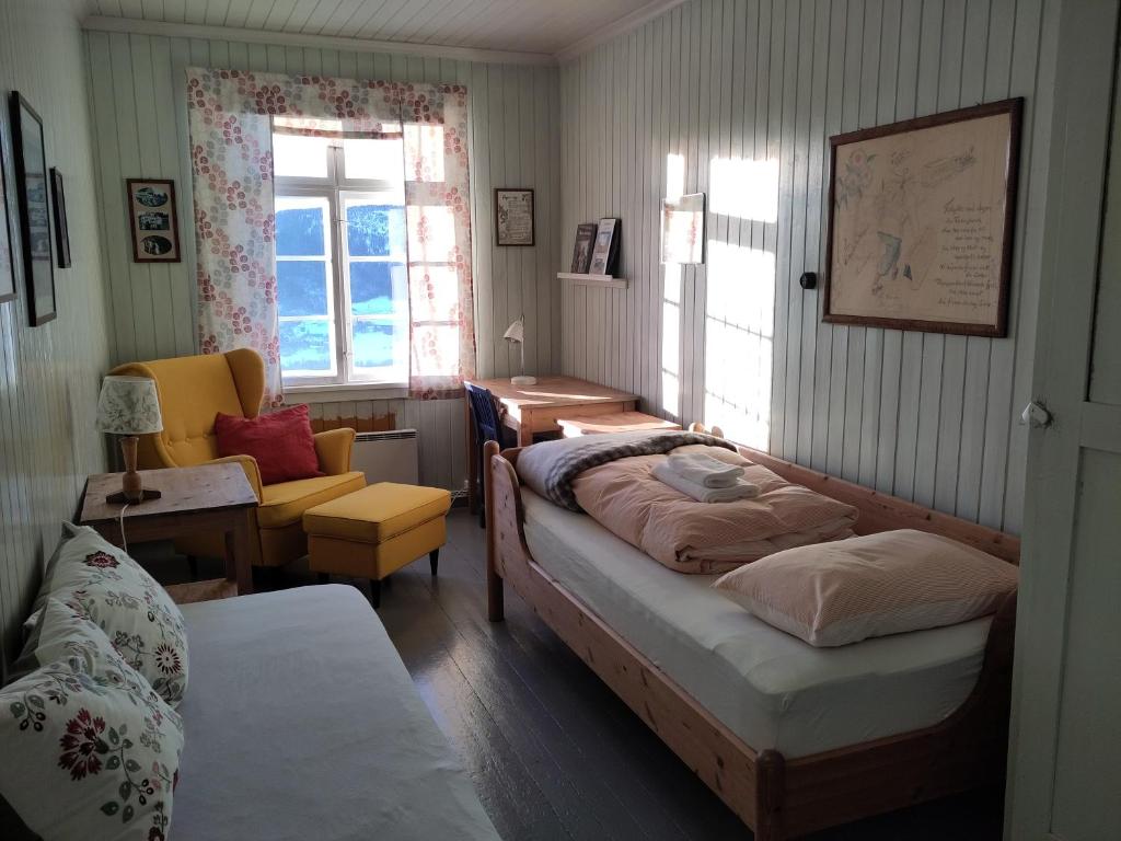 1 dormitorio con 2 camas, silla y ventana en Granum Gård, en Fluberg