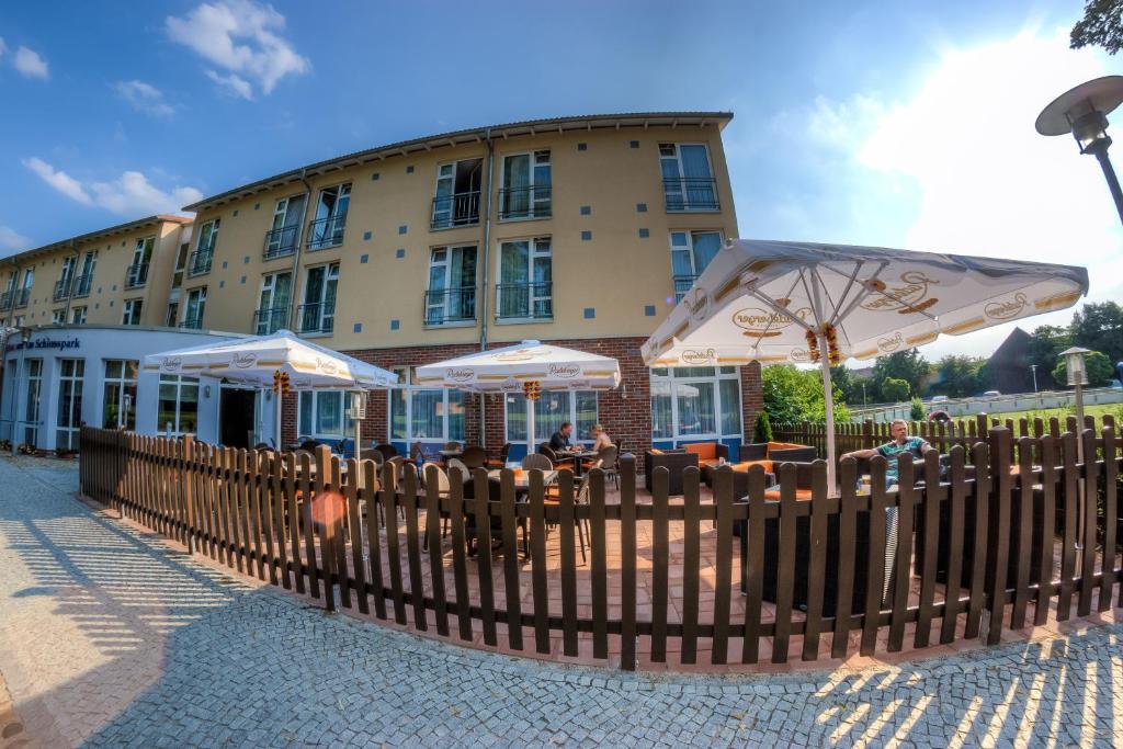 ein Restaurant mit Tischen und Sonnenschirmen vor einem Gebäude in der Unterkunft Hotel & Restaurant am Schlosspark in Dahme