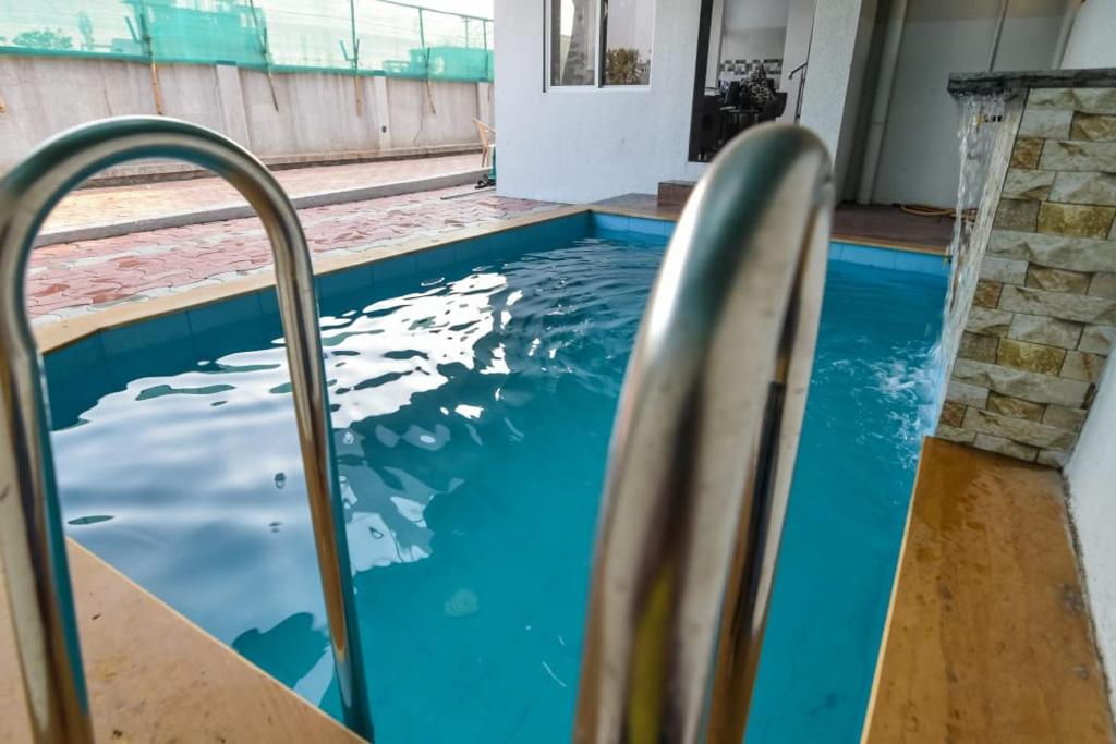 una piscina azul con barandilla metálica en EMPYREAN STAY ll 2BHK ll PRIVATE POOL ll GOOD LUCK VILLA ll FREE BREAKFAST en Lonavala