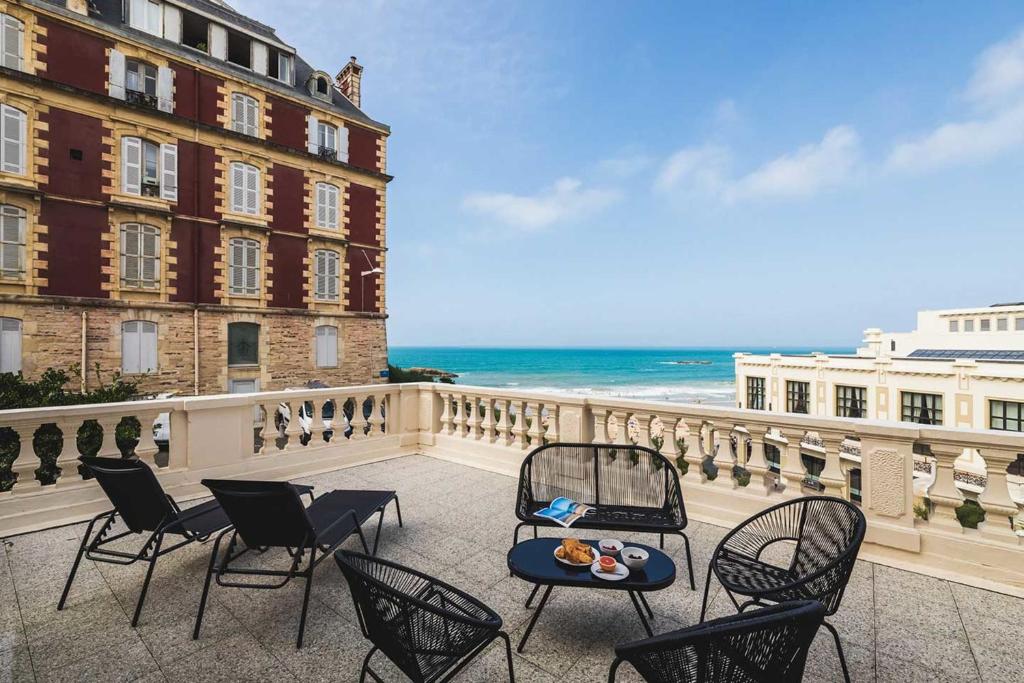 een balkon met stoelen en een tafel en de oceaan bij BLUE MOON KEYWEEK Seafront Apt with large Terrace and Parking Biarritz in Biarritz