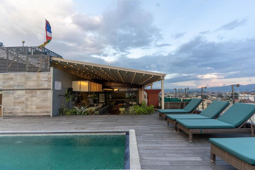 a rooftop patio with lounge chairs and a swimming pool at Hotel Shambala in Kathmandu