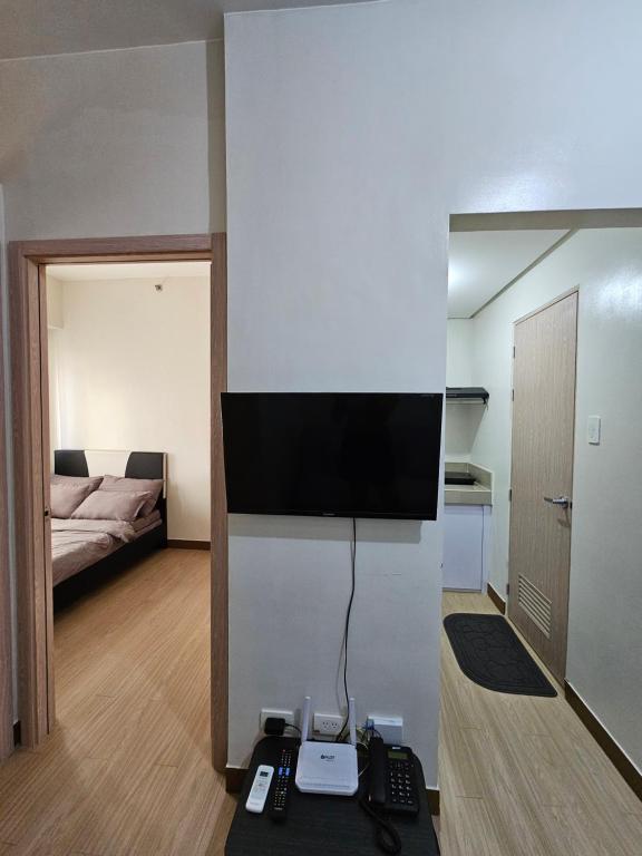 een woonkamer met een televisie en een kamer met een bed bij Trees Residence Condo in Manilla