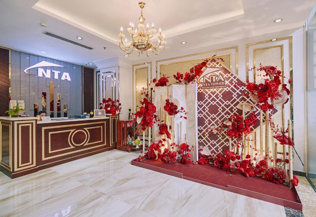 a lobby with a chandelier and red flowers at NTA Hotel - Serviced Apartments in Ho Chi Minh City