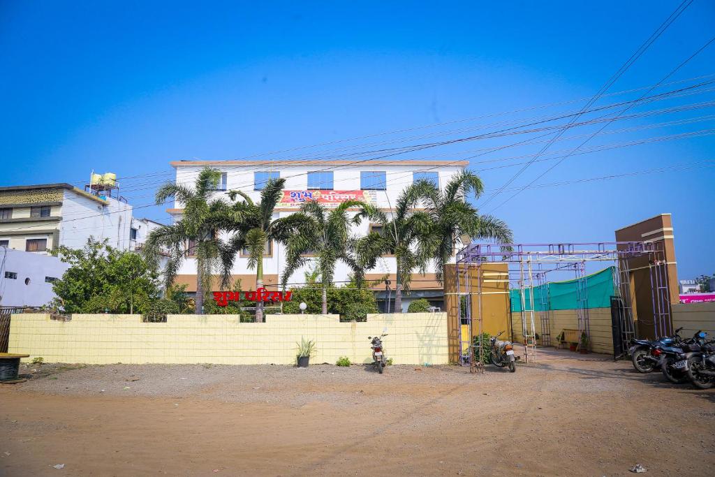 a building with palm trees in front of it at Shubh Parisar in Khandwa