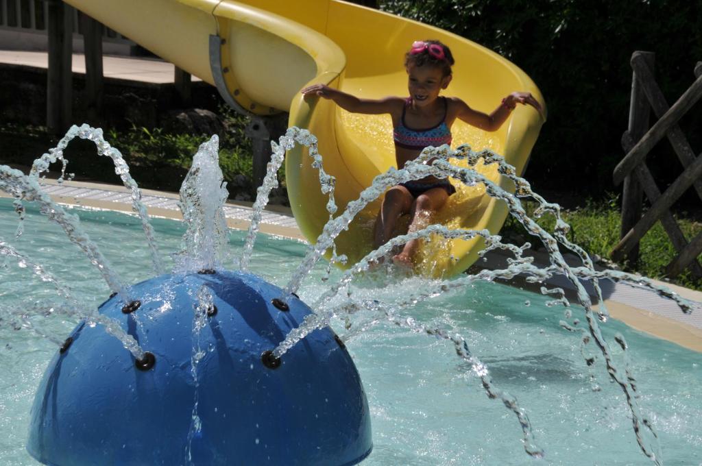 a young girl riding on a water slide at Camping La Mignardière in Ballan-Miré