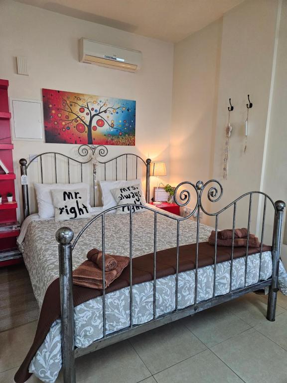 Un dormitorio con una cama de metal con una pintura en la pared en Kerynia Apartments, en Pafos