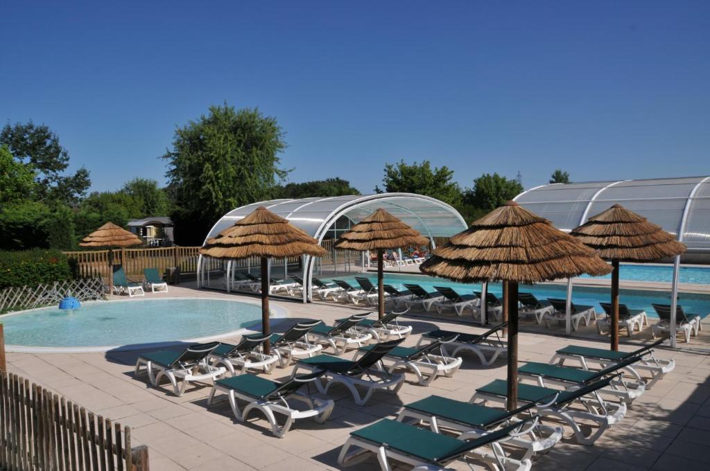 a group of chairs and umbrellas next to a pool at Camping La Mignardière in Ballan-Miré