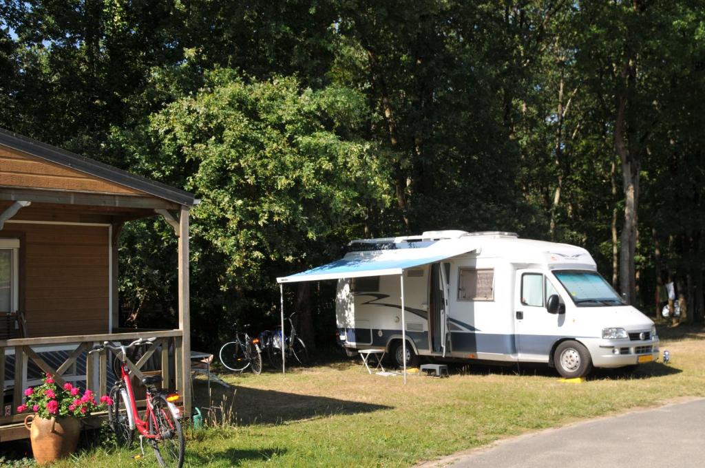 a white caravan parked in a yard next to a house at Camping La Mignardière in Ballan-Miré