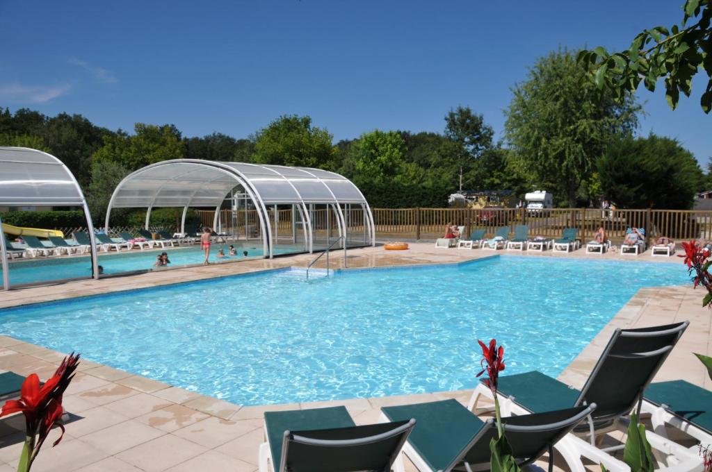 una gran piscina con sillas y dosel en Camping La Mignardière en Ballan-Miré