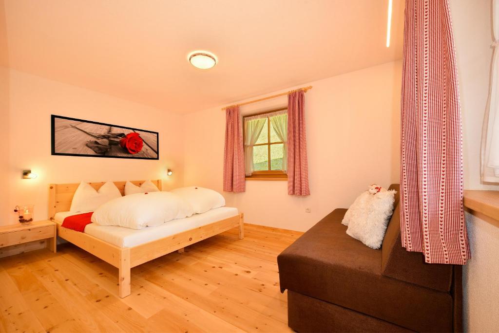 1 dormitorio con cama, sofá y ventana en Tratterhof Apt Eidechsspitze, en Vandoies