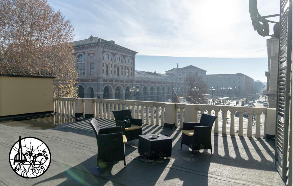 einen Balkon mit Stühlen und Tischen sowie ein Gebäude in der Unterkunft Hotel Bologna in Turin