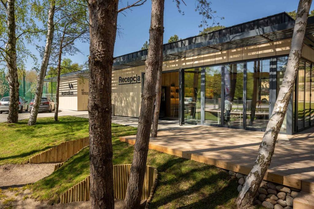 an office building with glass walls and trees at Apartamenty na Półwyspie Wydma&Las in Jastarnia