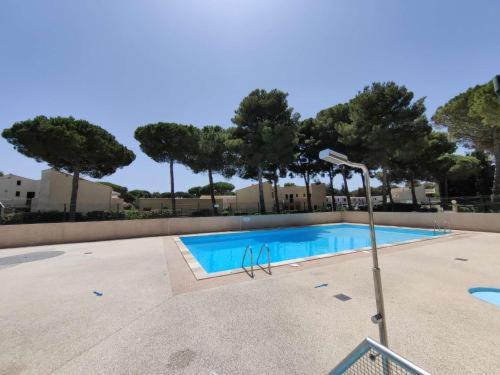 une piscine vide avec des arbres en arrière-plan dans l'établissement 5110 Hermitage 182, au Cap d'Agde