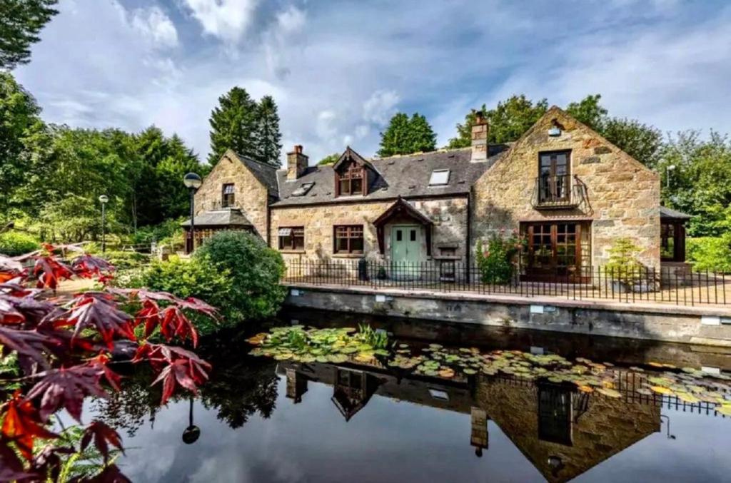 ein altes Steinhaus mit einem Teich davor in der Unterkunft Awakening Alchemy Retreat Centre in Inverurie