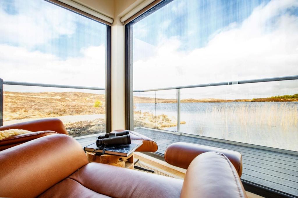 a room with a large window with a view of a lake at The Boathouse in Tomich