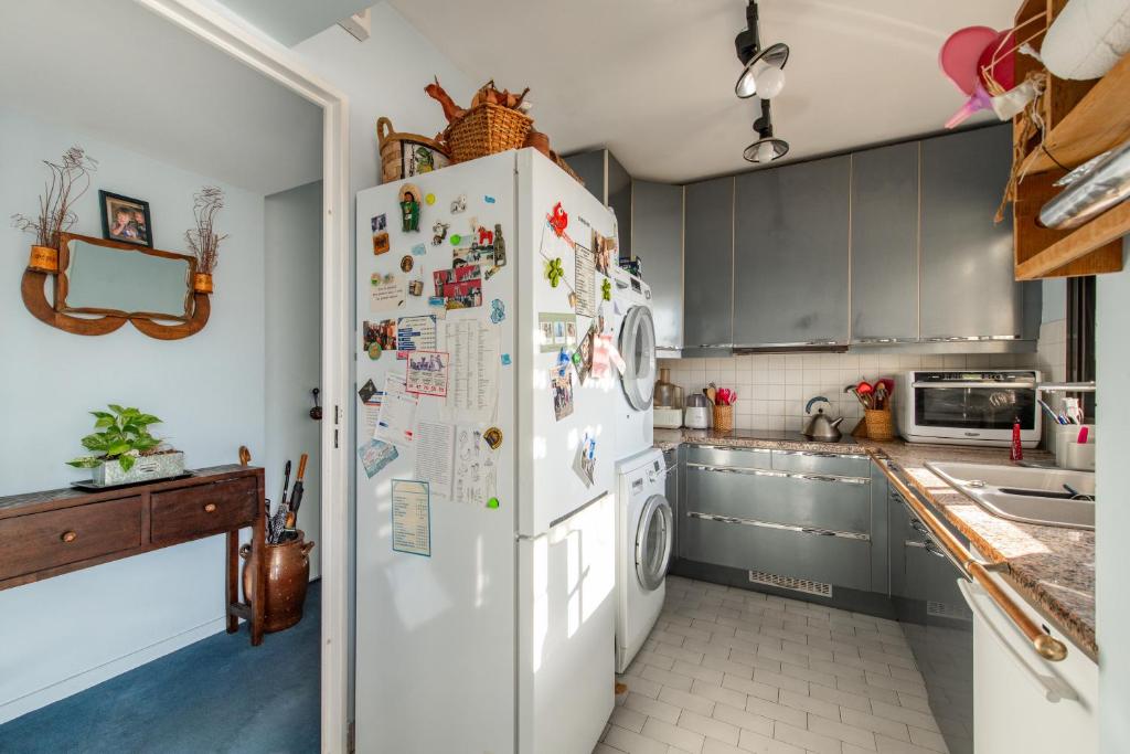 a kitchen with a white refrigerator with many magnets at 120 Grenelle - Spacieux Duplex avec vue sur la tour Eiffel in Paris