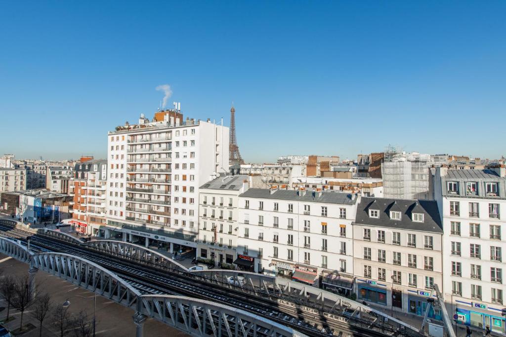 a view of a city with a train station and buildings at 120 Grenelle - Spacieux Duplex avec vue sur la tour Eiffel in Paris