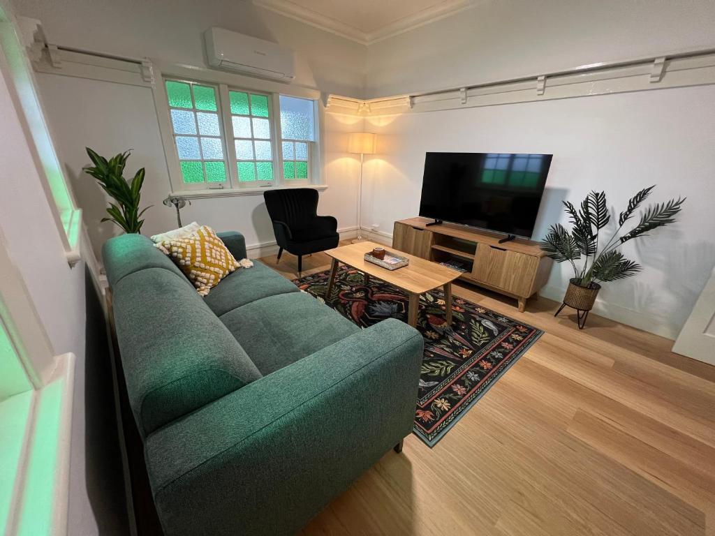 a living room with a green couch and a television at Sans Souci Apartments in Ingham
