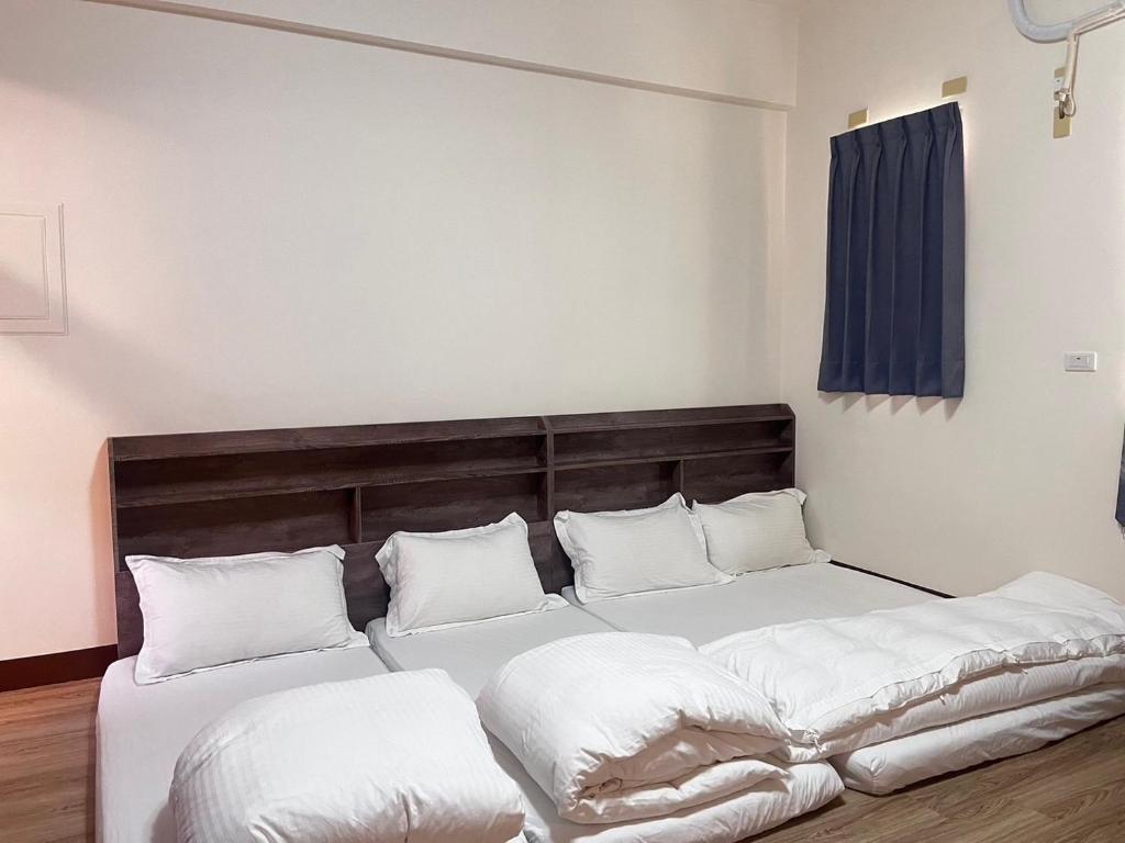 a bedroom with two beds with white sheets and pillows at Happy Life B&amp;B in Donggang