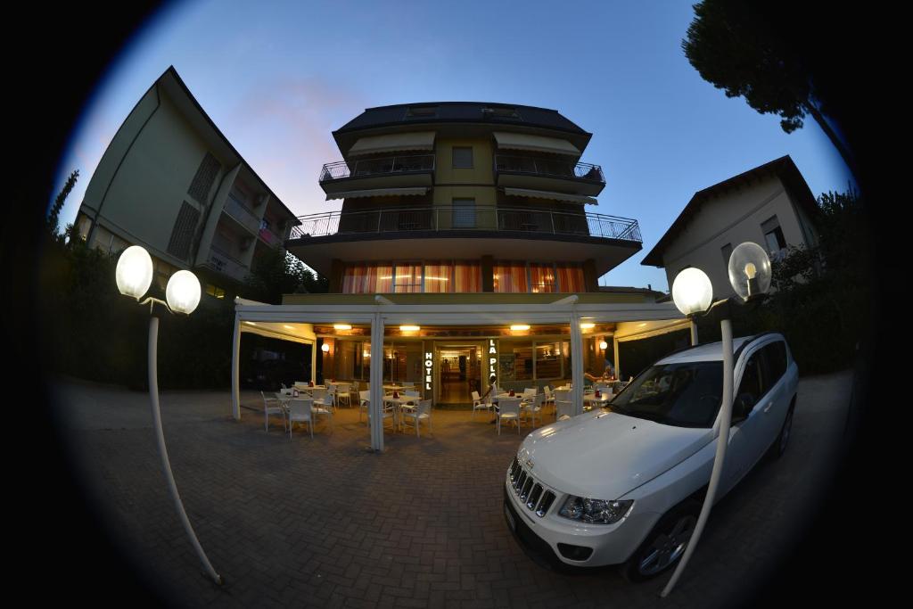 ein weißes Auto, das vor einem Gebäude parkt in der Unterkunft HOTEL LA PLAYA in Cervia