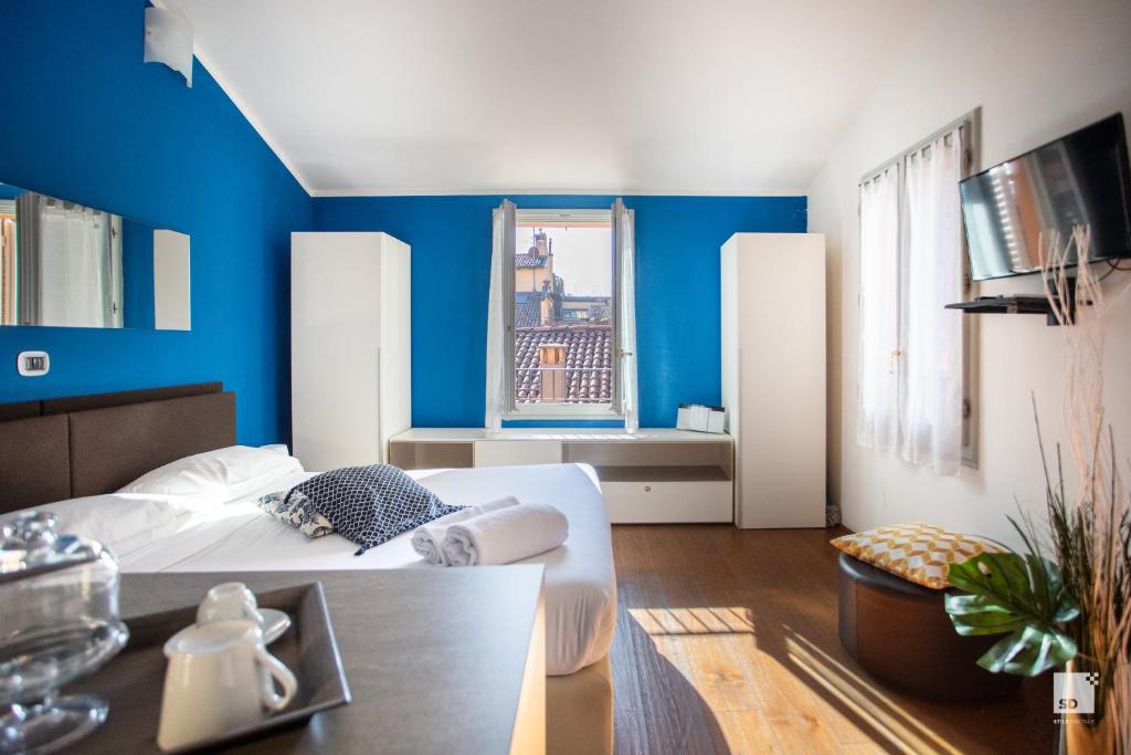 een slaapkamer met blauwe muren en een bed en een tafel bij Urbanicooh San Petronio - Torre Asinelli view in Bologna