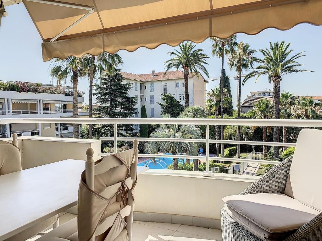 un balcon avec une table, des chaises et des palmiers dans l'établissement Cannes - 3 pieces a 15mn Palais, à Cannes