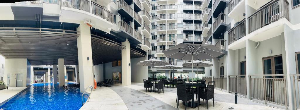 馬尼拉的住宿－S Residences-MOA，一座带桌子和遮阳伞的建筑中的游泳池
