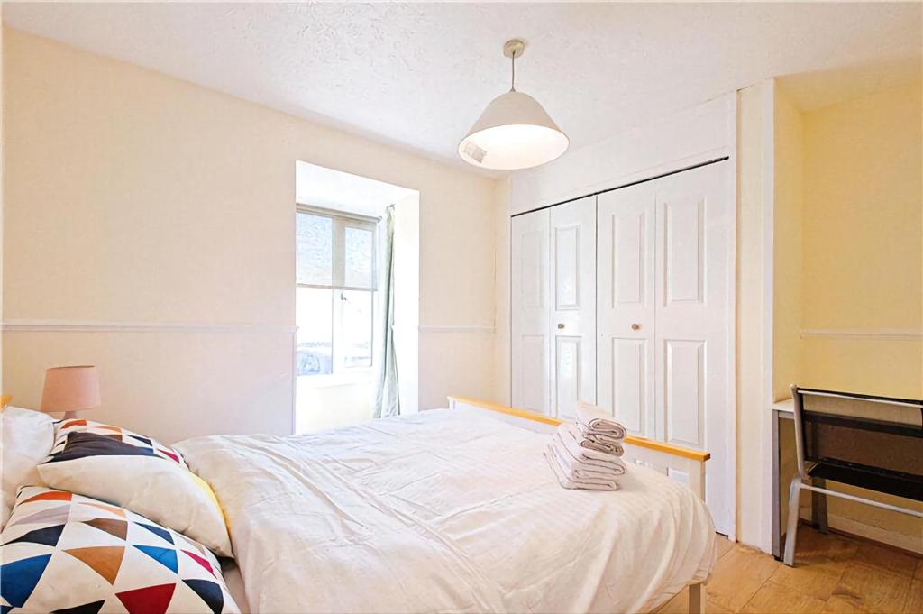 - une chambre blanche avec un lit et un piano dans l'établissement Manor Place Apartment Thamesmead, à Thamesmead