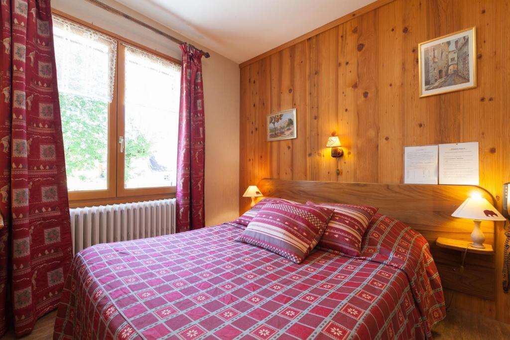 Schlafzimmer mit einem Bett mit einer roten Bettdecke in der Unterkunft Auberge des Montauds in Villard-de-Lans