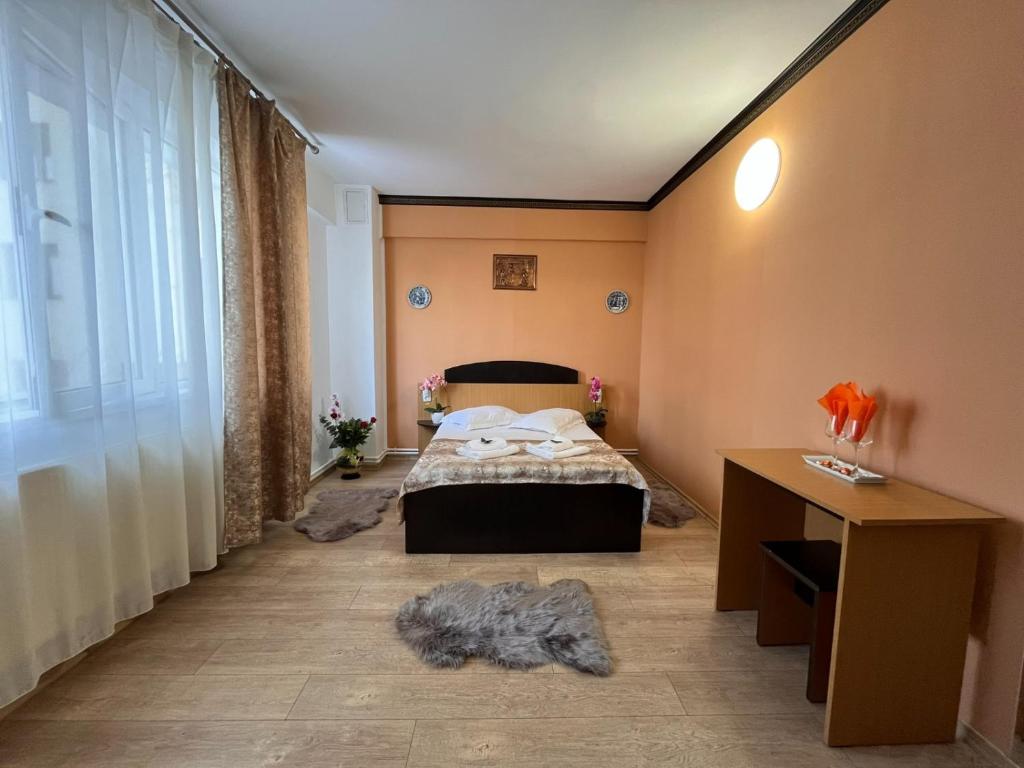 um quarto com uma cama, uma secretária e uma janela em Pensiunea Nys em Iaşi