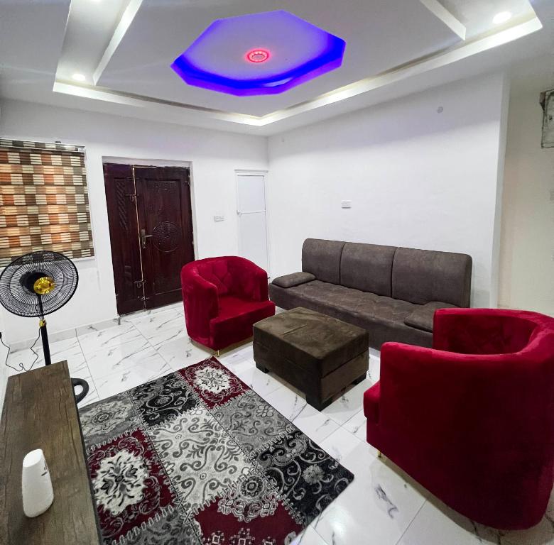 sala de estar con sofá y sillas rojas en Signature Residence en Calabar