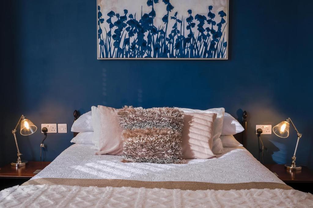 a bed with white sheets and pillows with blue walls at Cranmere Lichfield in Lichfield