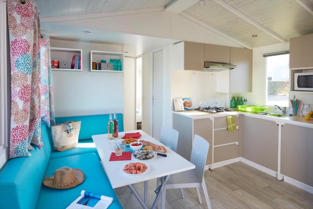 a small kitchen with a white table and a table and chairs at Camping La Mignardière in Ballan-Miré