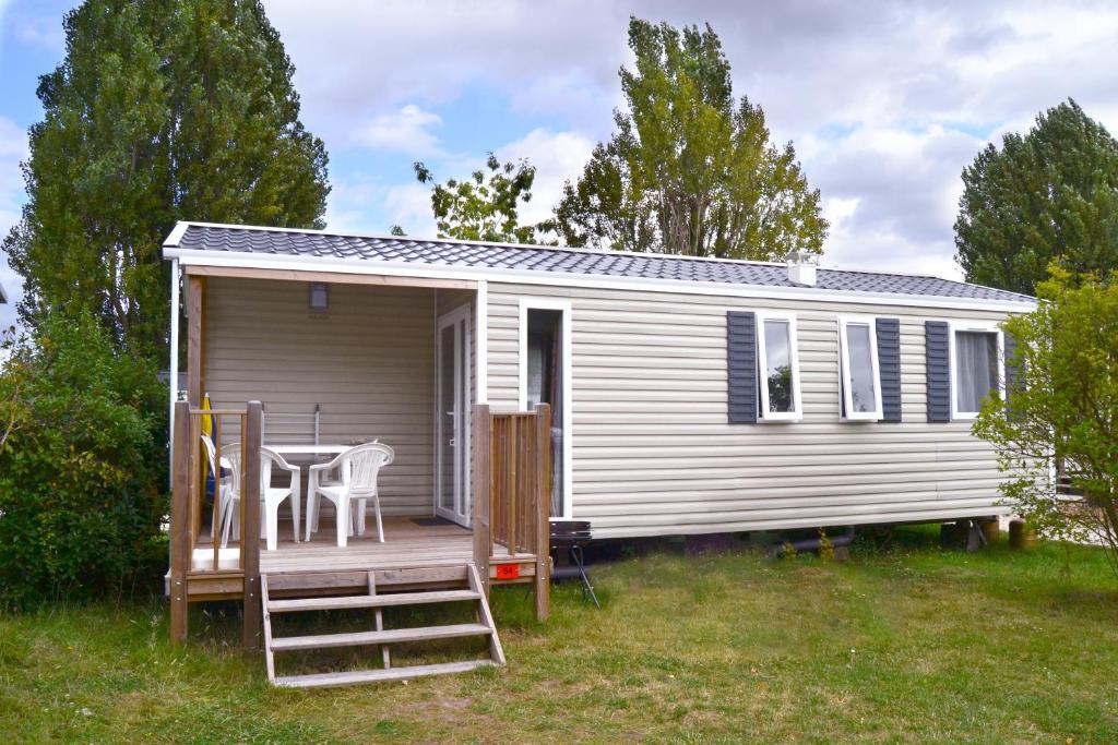 a tiny house with a deck and a table at Camping La Mignardière in Ballan-Miré