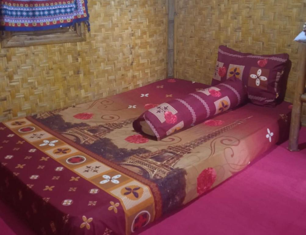 een bed in een kamer met een deken erop bij Farmer homestay in Tetebatu