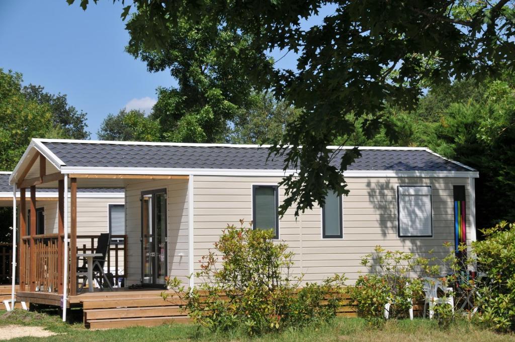 a tiny house with a porch and a deck at Camping La Mignardière in Ballan-Miré